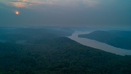 An aerial view of Esson Lake reflecting the sky on a hazy day in the summer during sunset