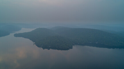 An aerial view of Esson Lake reflecting the sky on a hazy day in the summer during sunset