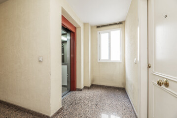 Stair landing of an urban residential apartment building with shiny granite floors and an elevator with a metal sliding door