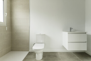 Fototapeta na wymiar Bathroom of a home with two-tone white and gray tiles and white porcelain sink on white lacquered wooden furniture with two drawers hanging on the wall