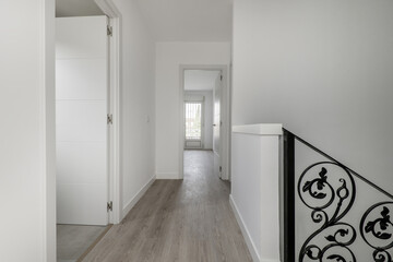 Distributor landing of a two-story single-family residential house with black metal handrails on a staircase with wooden steps