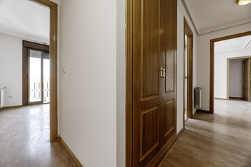 Hallway living room with access to several rooms, built-in wardrobes with light wooden floors throughout the house and walls painted plain white