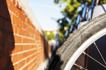 Wheel of a bicycle with metal spokes next to a brick wall