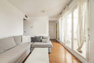 Living room of a home with a gray fabric sofa, large windows with access to a large furnished terrace