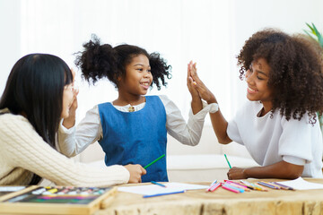 Happy joyful American - African ethnicity little girl learning and practicing drawing - painting.