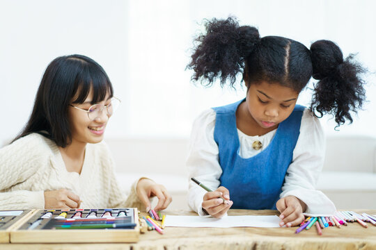 Happy joyful American - African ethnicity little girl learning and practicing drawing - painting.