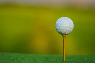 Golf ball is on tee at green lawn in a beautiful golf course with morning sunshine.