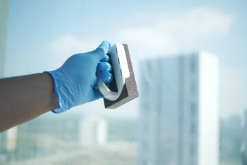  person hand in gloves cleaning window glass  - obrazy, fototapety, plakaty