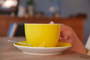 women holding a yellow color coffee cup 