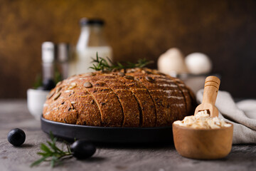 Freshly baked sourdough bread from whole grain flour and pumpkin seeds on a grid, olive oil and...