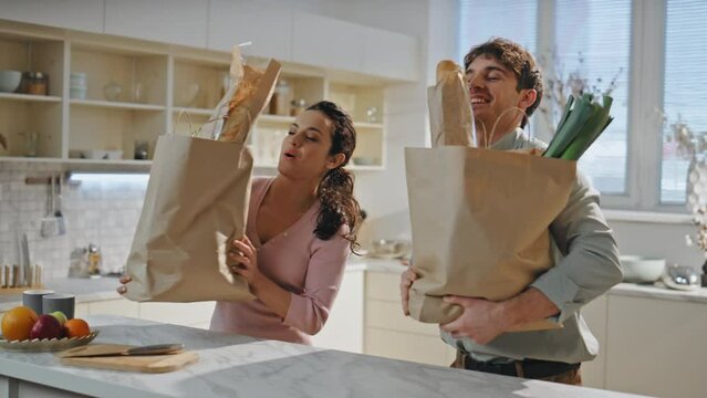 Husband bringing products bags to wife standing kitchen close up. Happy couple