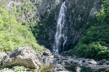 vue d'une grande chute dans la forêt lors d'une journée d'été ensoleillée avec un rocher en avant plan