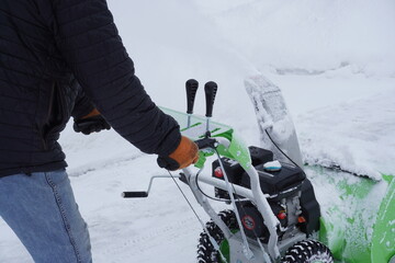A man cleans snow in the winter in the courtyard of the house,  man cleaning snow with a snow blower