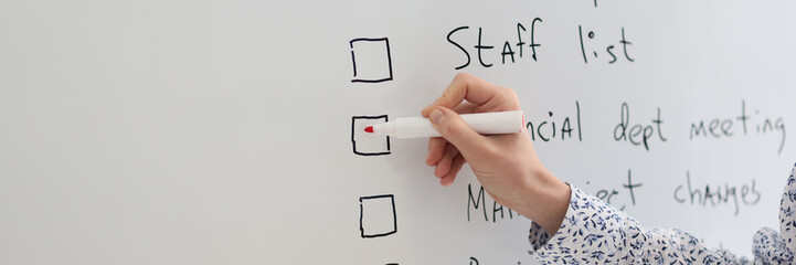 Female worker marks schedule points written on whiteboard