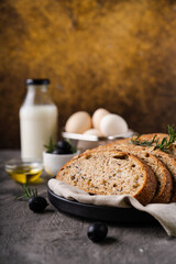 Freshly baked sourdough bread from whole grain flour and pumpkin seeds on a grid, olive oil and black olive on a rustic wooden table. Artisan bread.
