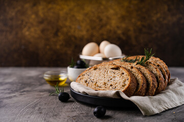 Freshly baked sourdough bread from whole grain flour and pumpkin seeds on a grid, olive oil and...