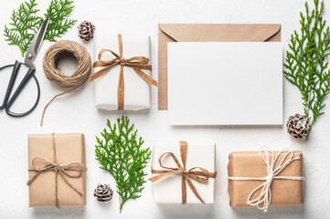 Christmas craft gift boxes, craft paper envelope and blank card and thuja branches, scissors and twine. Christmas or holiday card. Boxing Day. - obrazy, fototapety, plakaty