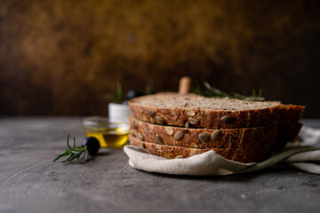 Freshly baked sourdough bread from whole grain flour and pumpkin seeds on a grid, olive oil and black olive on a rustic wooden table. Artisan bread.