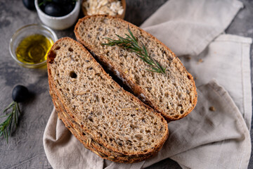 Freshly baked sourdough bread from whole grain flour and pumpkin seeds on a grid, olive oil and...