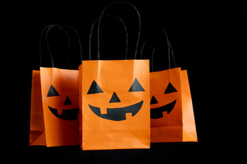 Halloween treat bags for trick-or-treating sweets candies. Paper gift bags with handles, for candy and other goodies. Decorated with spooky Jack-o'-lantern face. Trick or Treat party favor bags. - Powered by Adobe