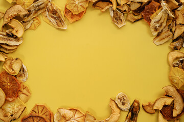 Obraz na płótnie Canvas Oval ornament made of thin slices of dried fruits on a yellow background