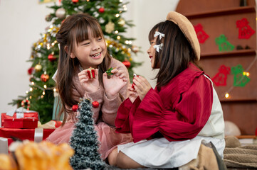Two cute young Asian girls are enjoying playing in the living room on a Christmas holiday together.