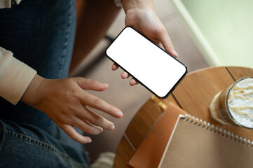 Obraz premium Top view image of a woman in casual clothes using her smartphone while relaxing in a coffee shop.