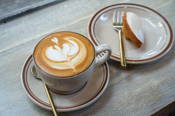 Hot coffee latte with latte art milk foam in cup mug and Homemade white chocolate madeleines on...