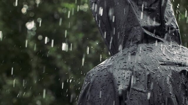 Closeup unrecognizable person in heavy rain, young man in water proof black coat