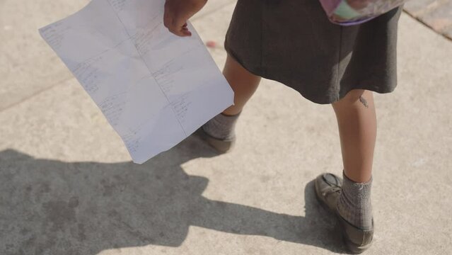 Slow Motion Footage Of A Student Kid Walking Holding An Exam Paper In Johannesburg, South Africa