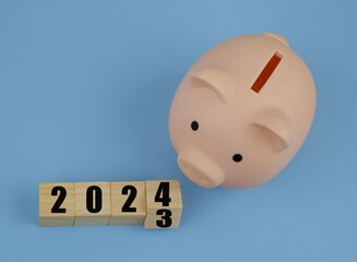 Piggy bank and flipping numbers on wooden cubes 2023 and 2024.