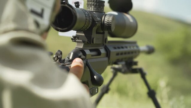 The shooter takes aim with a sniper rifle to shoot at the target. Close-up