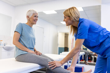 Fototapeta premium Professional orthopedist examining senior woman patient's leg in clinic. physical therapist doing rehabilitation procedure to senior woman on massage table.