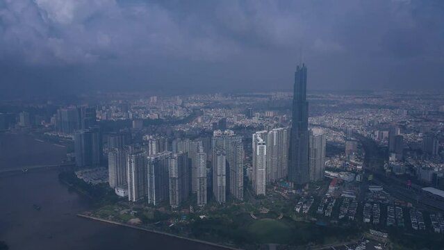 Aerial orbit of Landmark building Vietnam in early morning. Drone travels in ccw direction around skyscraper in clouds and panorama of skyline and Saigon River. Symbol of Ho Chi Minh City and SE Asia.