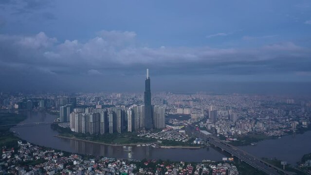 Aerial orbit of Landmark building, Vietnam in early morning. Drone travels in ccw direction around skyscraper and panorama of skyline and Saigon River. Symbol of Ho Chi Minh City and Southeast Asia.