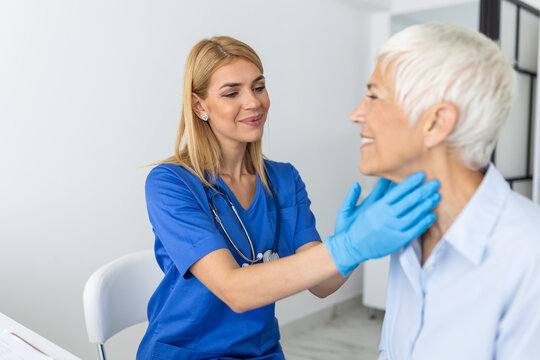 medicine, healthcare and medical exam concept - doctor or nurse checking patient's tonsils at hospital. Endocrinologist examining throat of senior woman in clinic