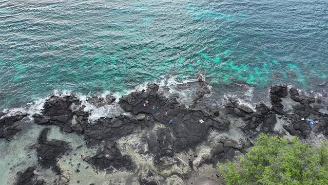Aerial ocean Two Step rocky beach Kona Hawaii overh. Beautiful cove bay with blue Pacific ocean water. Snorkel and scuba dive vacation destination. Black volcanic lava rock. Recreation and relaxation.