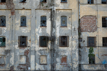 Dilapidated building facade. Cracked and pealed exterior plaster on brick wall and old window...