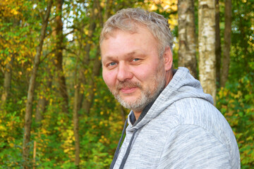 Gray-haired man with beard on honking in autumn park