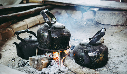 Old kettle for boiling water on stove In kitchen the countryside. Old black kettle stands on fire...