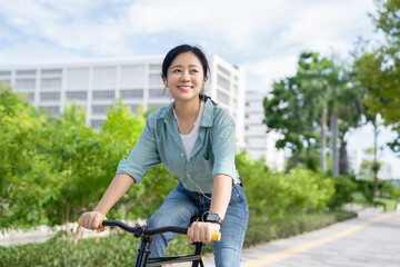 Attractive Asian woman in casual clothes riding a bicycle in the park on vacation