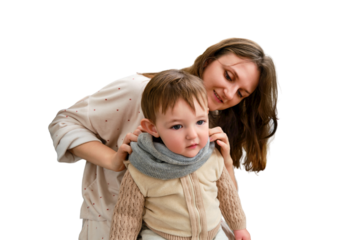 Mother puts a warm scarf on the toddler baby, isolated on a white background. Woman mom dressing warm clothes on child for winter walk in cold weather. Kid aged one year and three months