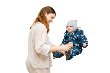 Mother puts a warm scarf on the toddler baby, isolated on a white background. Woman mom dressing warm clothes on child for winter walk in cold weather. Kid aged one year and three months