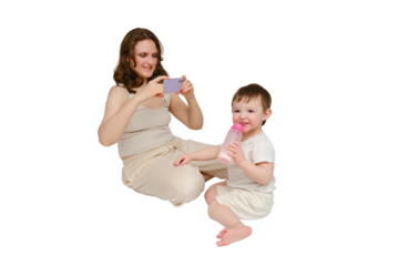 Woman mother takes a picture of a baby with a phone on a studio, isolated on white background. Mom blogger shoots a video from a child for a blog. Kid about two years old (one year nine months)