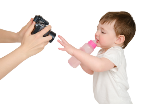 Woman mother photographs baby on photo camera, studio, isolated on white background. Mom blogger shoots a video from a child for a blog. Kid about two years old (one year nine months)