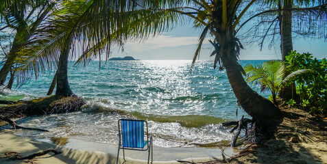 Beach scene with beach chair under coconut palms, Chang island, Thailand.