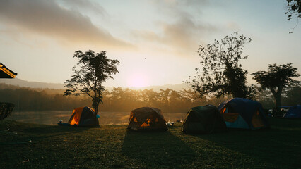 Camping and tent near lake in sunrise. Beautiful sunset on the lake. There is a tent nearby. Silhouette © SandyHappy
