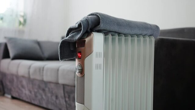 The blanket lies on the electric heater that is turned on. Concept of fire hazard and fire in the house. Copy space for text