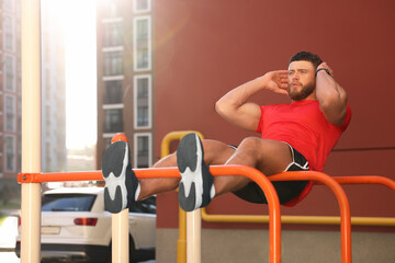 Man doing abs exercise on parallel bars at outdoor gym