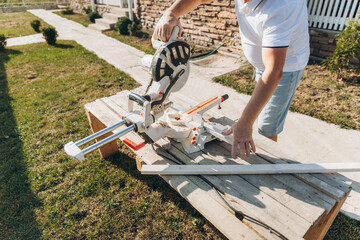 male carpenter cuts a wooden board with an electric saw at home. builder.